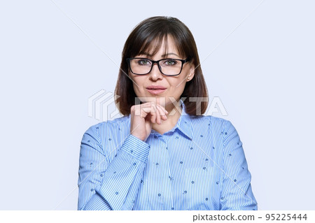 Portrait of serious middle-aged woman on light studio background Portrait of serious middle-aged woman on light studio background 95225444
