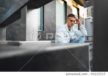 Young casual man sitting on stairs alone on street 95225517