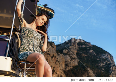 Young pretty woman in floral dress posing on yacht in sea 95225588