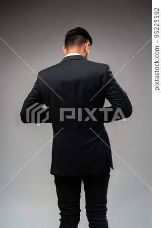 Young businessman from the back standing on gray background 95225592
