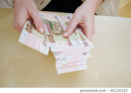 a woman holds in her hands and recalculates Russian banknotes of 100 rubles.  95226187