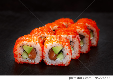appetizing sushi roll california with avocado shrimp cheese and masago caviar on a black background. appetizing sushi roll california with avocado shrimp cheese and masago caviar on a black background. 95226352
