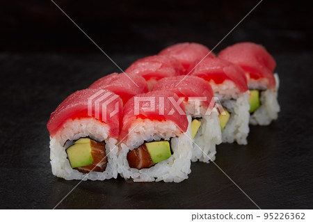 Sushi roll Maguro with tuna, shrimp, salmon, smoked eel, avocado, philadelphia cheese on black background. Sushi menu. Japanese food. Sushi roll Maguro with tuna, shrimp, salmon, smoked eel, avocado, philadelphia cheese on black background. Sushi menu. Japanese food. 95226362