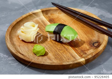 Sushi covered with avocado on wooden board gray stone background. Sushi covered with avocado on wooden board gray stone background. 95226405