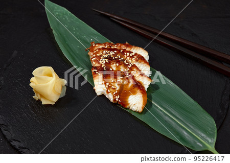 Fresh seafood sashimi smoked eel on slate board with wasabi and ginger on black background 95226417