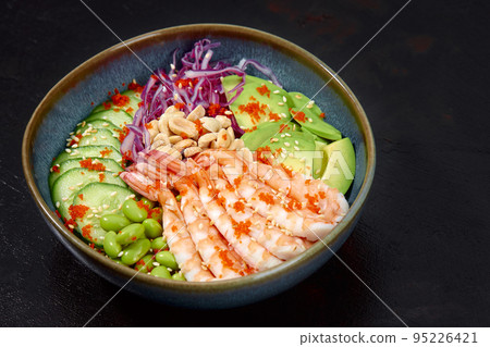 Top view on poke salad with red shrimps and green vegetable in the bowls on gray background. Copy space. Top view on poke salad with red shrimps and green vegetable in the bowls on gray background. Copy space. 95226421
