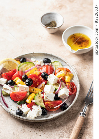 Traditional greek salad with feta cheese, tomatoes, red onion, cucumber, pepper, olive oil and italian herbs served on brown background with rustic fork 95226637
