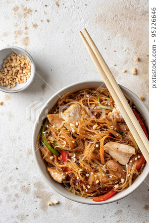 Funchose salad with chicken and vegetables in bowl with wooden chopsticks on textured background, top view, flat lay. Asian food menu 95226646
