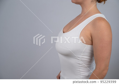 Close-up of a female breast before and after augmentation. A woman tries on a silicone implant before surgery. 95229399