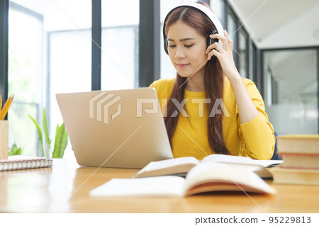 Young woman studying or working online using laptop and wearing headphones. Young woman studying or working online using laptop and wearing headphones. 95229813