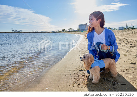 女人和她的狗在沙灘上玩耍 95230130
