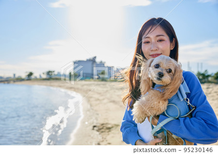 Woman playing on the beach with her dog 95230146