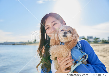 Woman playing on the beach with her dog 95230147