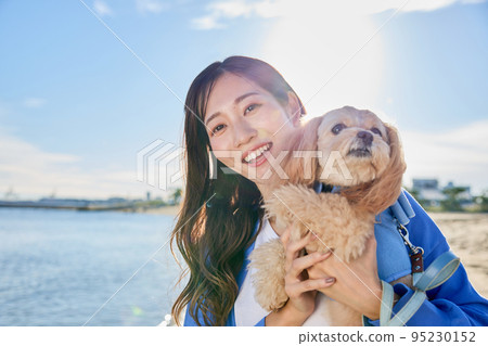 Woman playing on the beach with her dog 95230152