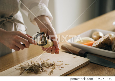 Woman peeling potatoes in the kitchen 95230250