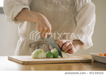 Woman cutting onions in the kitchen Woman cutting onions in the kitchen 95230420