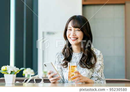 A young woman relaxing in a cafe 95230580