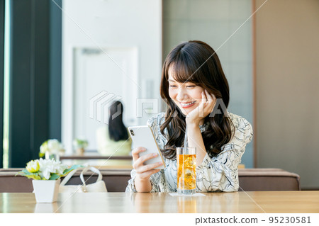 A young woman relaxing in a cafe 95230581