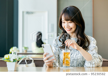 A young woman relaxing in a cafe 95230582