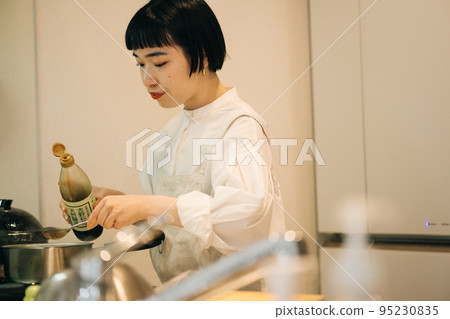 A woman who puts soy sauce in a pot 95230835