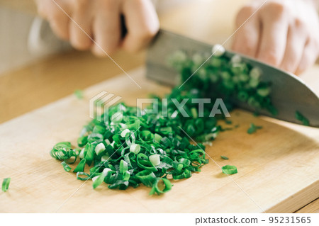 Woman's hand cutting green onions in the kitchen 95231565