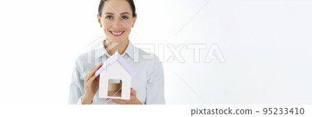Smiling female realtor is holding house closeup 95233410