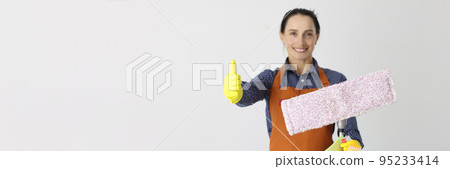 Employee of cleaning company with mop holds thumbs up gesture Employee of cleaning company with mop holds thumbs up gesture 95233414