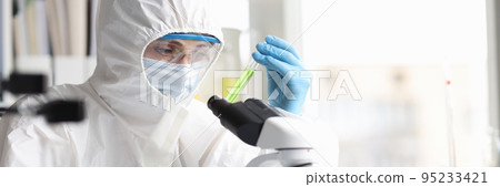 Scientist in protective suit studies toxic poisonous liquids in laboratory 95233421