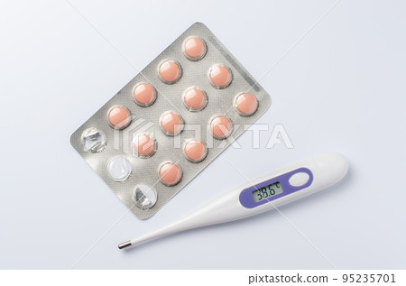 Medical electronic thermometer and tablets on a white background. The concept of diagnosis and treatment of diseases. 95235701
