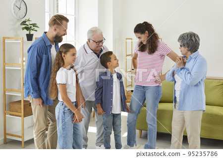 Happy mother together with rest of family standing in living room and talking to children 95235786