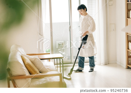 Woman vacuuming in the living room Woman vacuuming in the living room 95240736