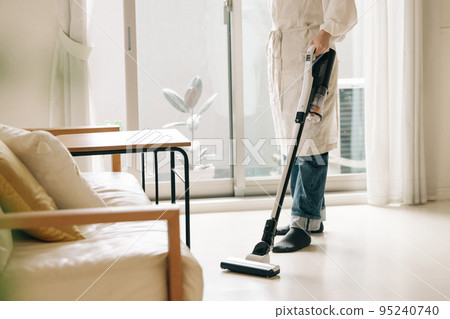 Woman vacuuming in the living room Woman vacuuming in the living room 95240740