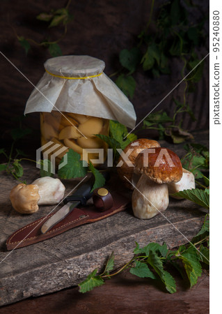 Porcini mushroom commonly known as Boletus Edulis, glass jar with canned mushrooms and knife on vintage wooden background.. Porcini mushroom commonly known as Boletus Edulis, glass jar with canned mushrooms and knife on vintage wooden background.. 95240880