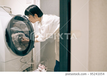 A woman using a drum-type washer/dryer 95241054