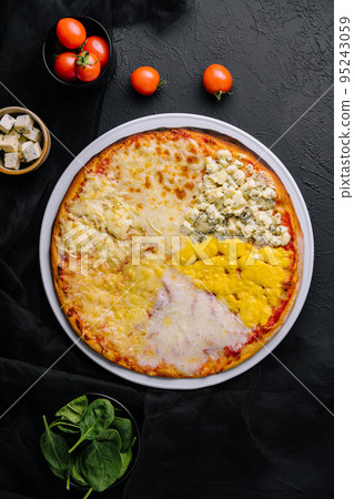 different types of cheese on a big pizza 95243059
