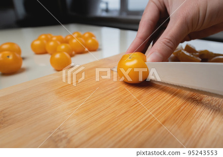 The chef cuts vegetables into a salad on a wooden cutting board in the kitchen at home. Cooking. The woman uses a knife and cooks The chef cuts vegetables into a salad on a wooden cutting board in the kitchen at home. Cooking. The woman uses a knife and cooks 95243553