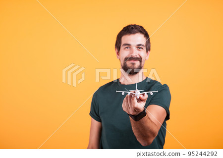 Happy smiling man showing a toy plane to the camera in travel concept image. Tourism and freedom Happy smiling man showing a toy plane to the camera in travel concept image. Tourism and freedom 95244292