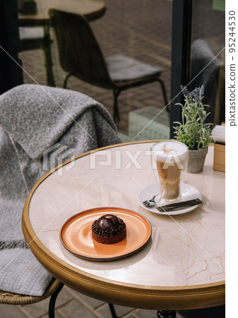 Latte coffee with cake on the table in the outdoor cafe Latte coffee with cake on the table in the outdoor cafe 95244530