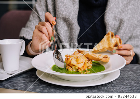woman eating spinach soup with seafood woman eating spinach soup with seafood 95244538