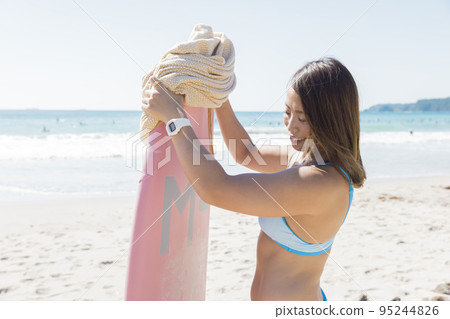 A young woman who removes the surfboard cover and prepares to ride a wave.Use in an adult or other negative image is prohibited. 95244826
