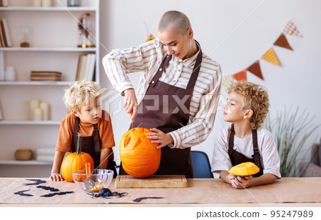 Children and mom making Jack-o-Lantern together at home, carving Halloween pumpkin 95247989