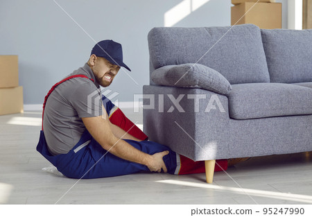 While lifting heavy furniture, young worker got his leg pinned under heavy couch 95247990