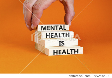 Mental health psychological symbol. Concept words Mental health is health on wooden blocks on a beautiful orange table orange background. Psychologist hand. Psychological mental health concept. Mental health psychological symbol. Concept words Mental health is health on wooden blocks on a beautiful orange table orange background. Psychologist hand. Psychological mental health concept. 95248402