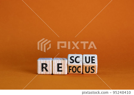 Refocus and rescue symbol. Businessman turned cubes and changed the word 'refocus' to 'rescue'. Beautiful orange table, orange background. Business refocus and rescue concept. Copy space. 95248410
