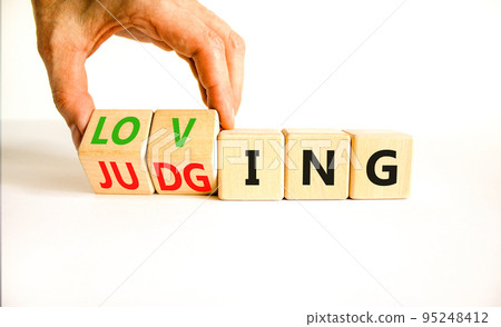 Loving or judging symbol. Concept words Loving or Judging on wooden cubes. Businessman hand. Beautiful white table white background. Business loving or judging concept. Copy space. 95248412