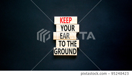 Keep your ear to the ground symbol. Concept words Keep your ear on the ground on wooden blocks. Beautiful black table black background. Business keep your ear on the ground concept. Copy space. 95248423
