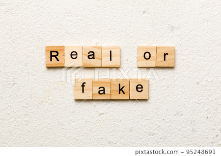 Real or fake word written on wood block. Real or fake text on cement table for your desing, Top view concept 95248691