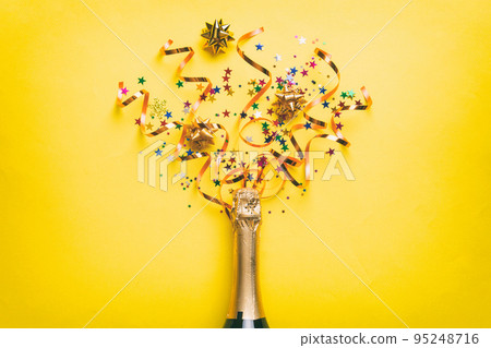 Creative flat lay composition with bottle of champagne and space for text on color background. Champagne bottle with colorful party streamers. holiday or christmas concept 95248716