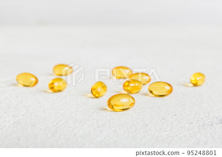 Heap of yellov pills on colored background. Tablets scattered on a table. Pile of red soft gelatin capsule. Vitamins and dietary supplements concept 95248801
