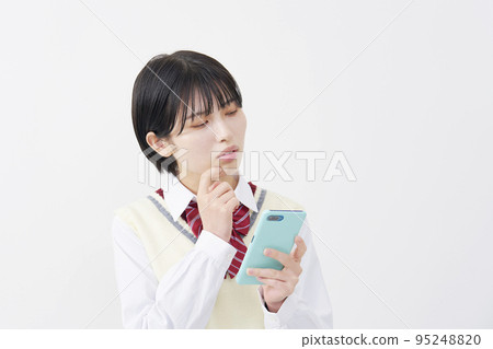High school student holding a smartphone and thinking White background High school student holding a smartphone and thinking White background 95248820